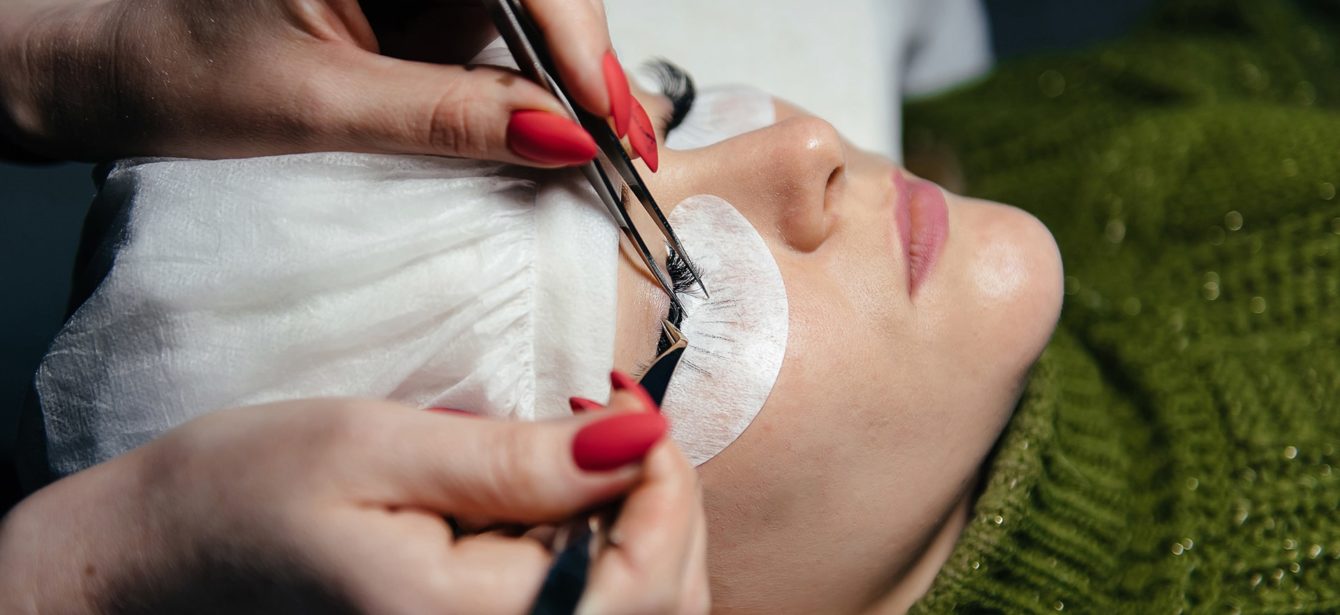 eyelash-extension-process-closeup-portrait-young-girl-woman-with-long-thick-eyelashes-eyes-closed-hand-cosmetologist-adding-more-eyelashes-her